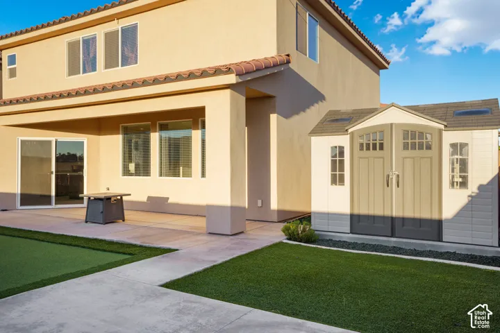 Covered patio with sliding glass door, paved hardscaping, and artificial turf