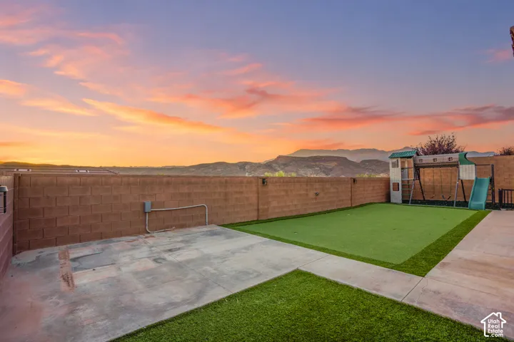 Backyard featuring a concrete patio, artificial turf, and a block perimeter fence