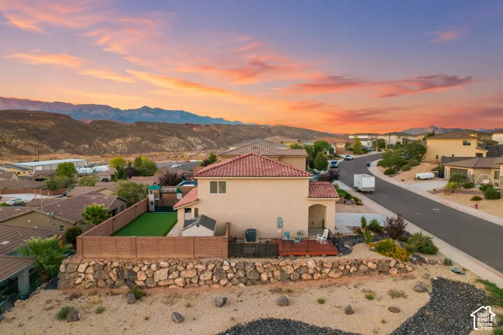 Striking Southwestern-style residence showcasing a terra cotta tile roof, stucco exterior, and manicured landscape with native drought-resistant plantings