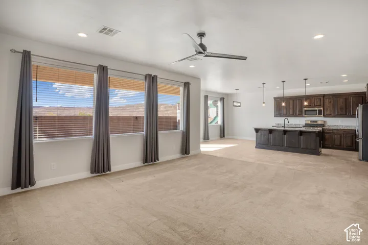 Recessed lighting, ceiling fan, dark wood cabinetry, integrated microwave, and a kitchen island with pendant lighting