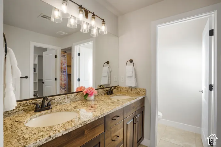 Primary Bathroom. Dual vanity with integrated sinks, wood-finish cabinetry, granite countertop, and bronze fixtures