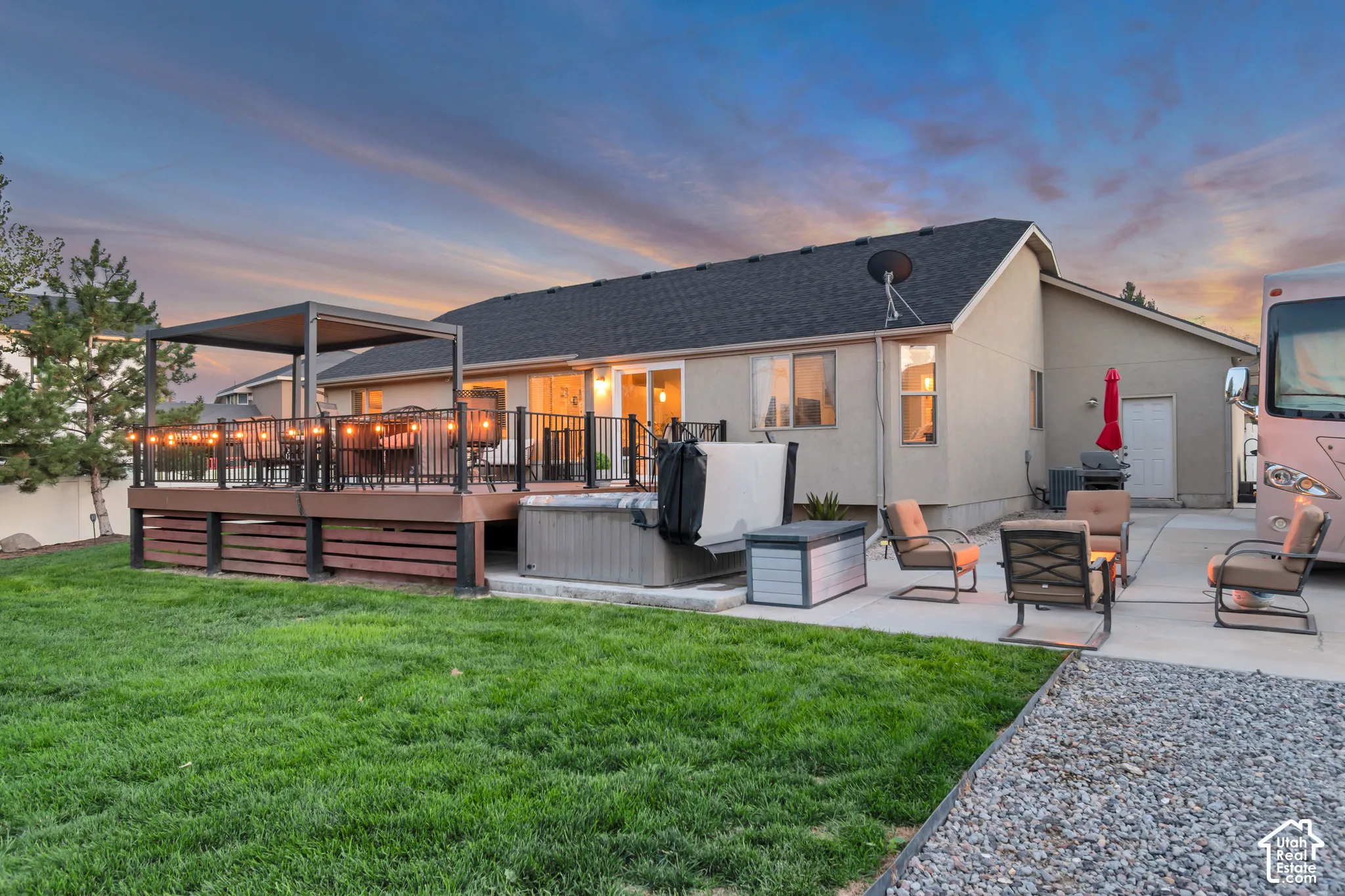 Expansive backyard featuring a large elevated deck with a pergola, a built-in hot tub, and an extended concrete patio