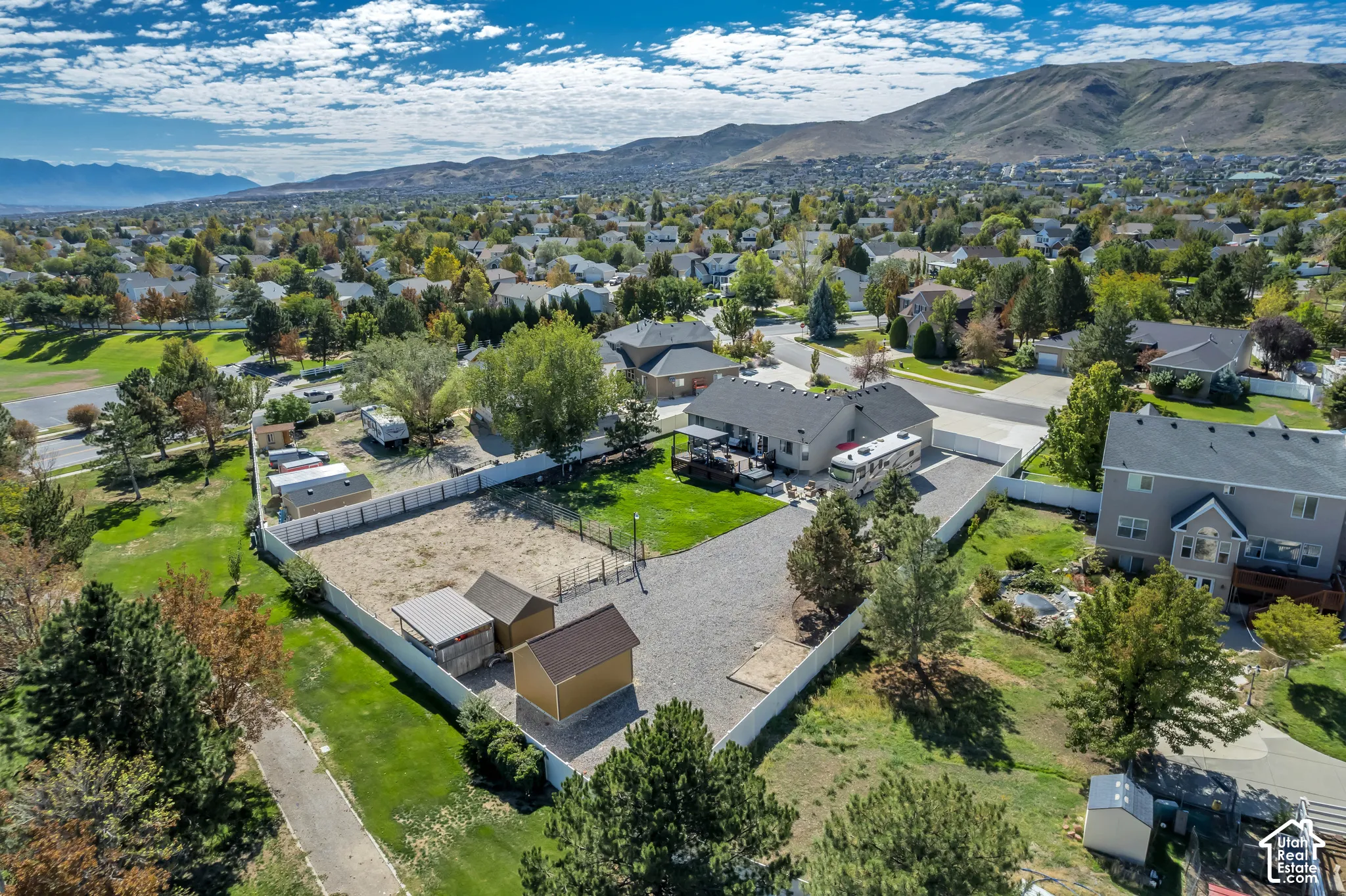 Expansive property featuring a gravel driveway, fenced backyard, and detached sheds
