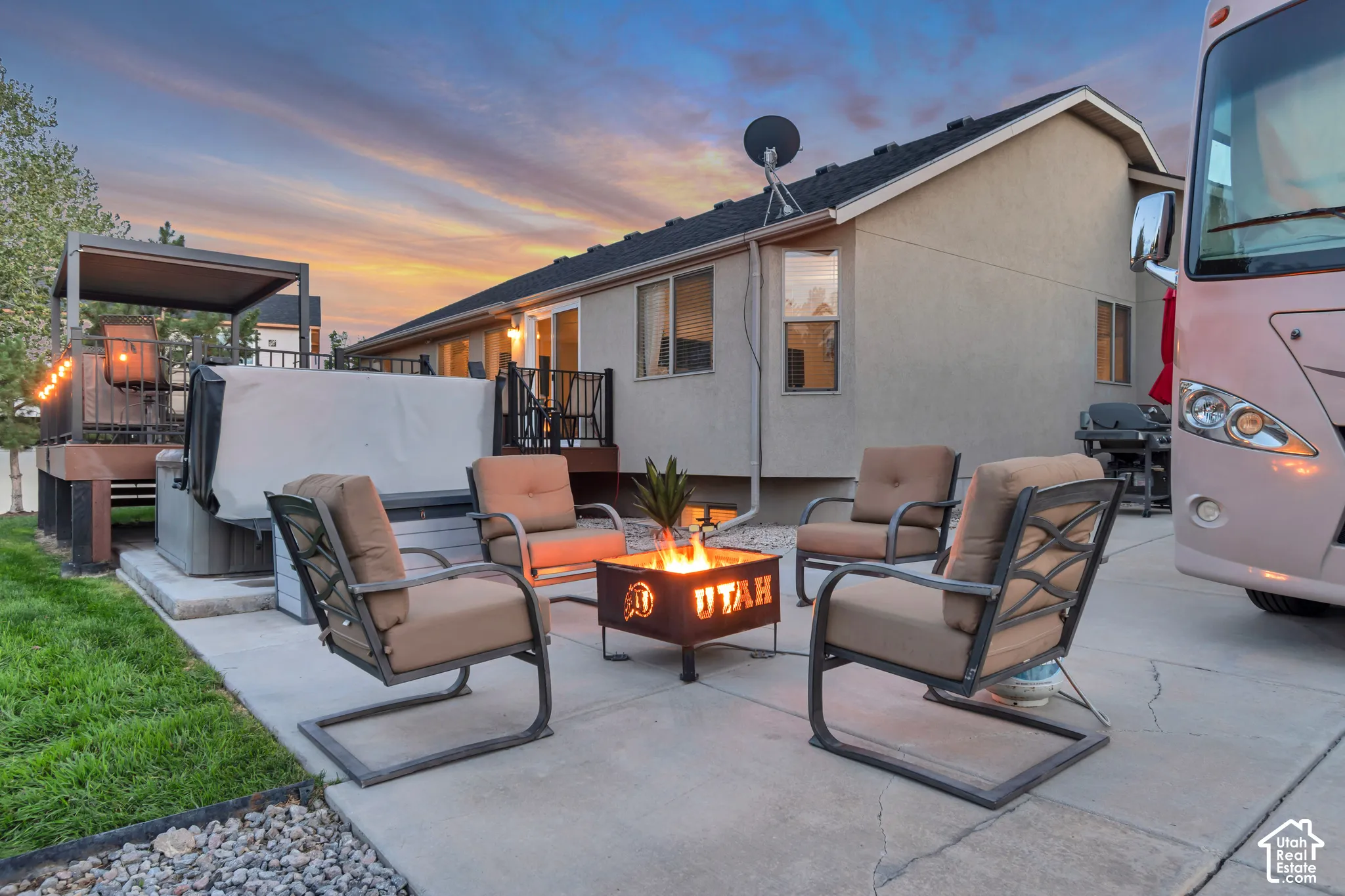 Concrete patio with a built-in fire pit, covered hot tub area, and a raised wooden deck with railings