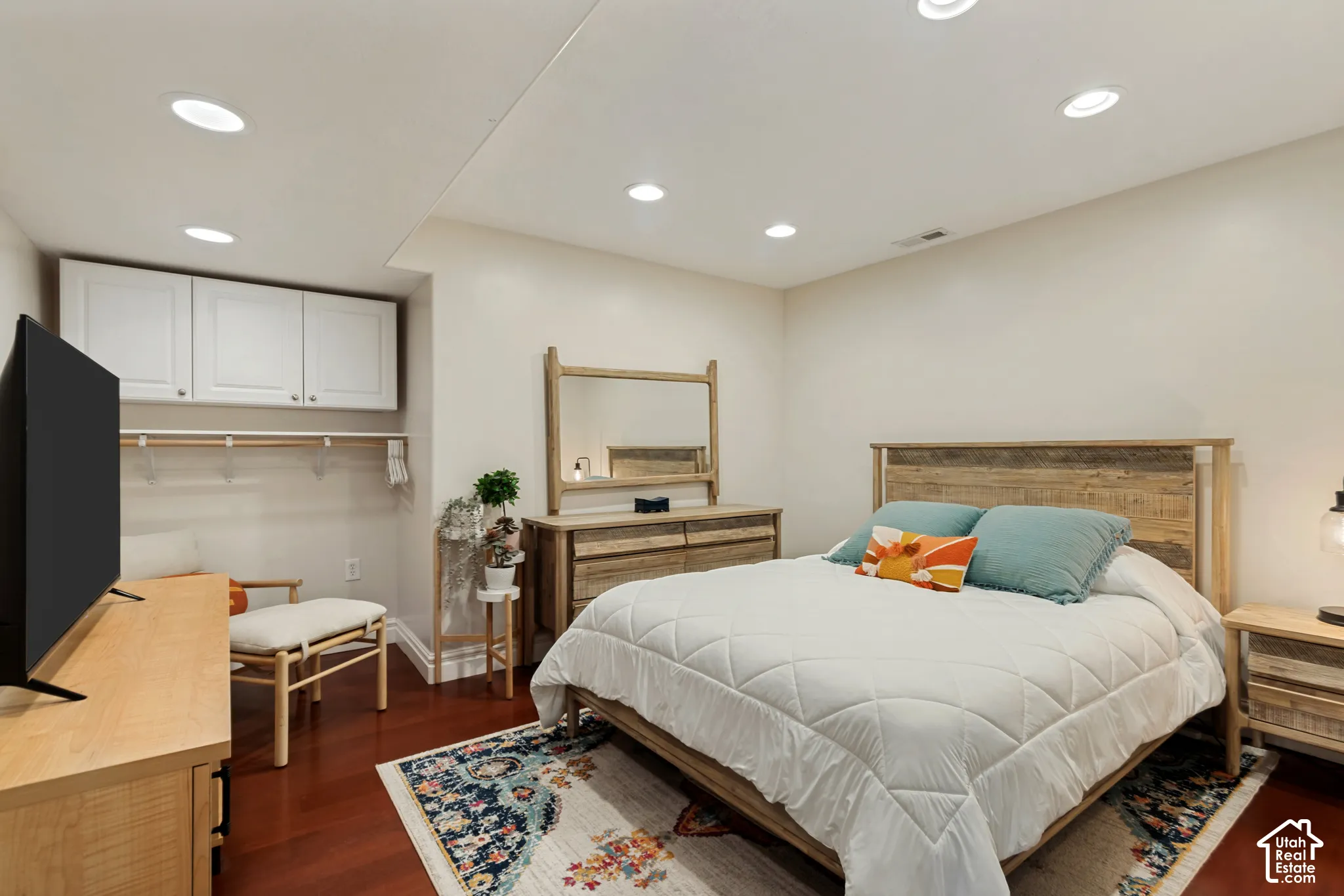 Recessed lighting, wood-finish flooring, and white cabinetry with hanging rod
