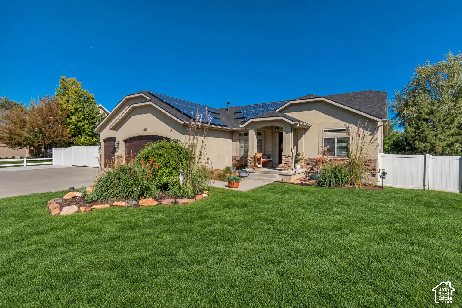 Stucco exterior with stone accents, covered entry, and solar panels