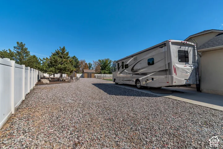 Expansive gravel parking area, white privacy fencing, and a separate storage shed