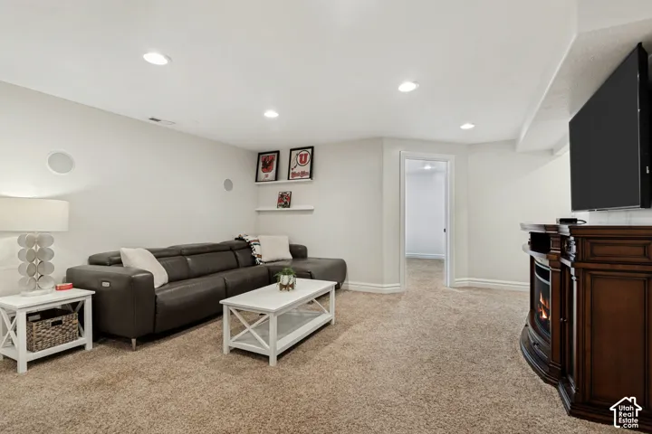 Recessed lighting, light-colored carpeting, built-in shelving, and a dark wood-finish media console with an integrated fireplace