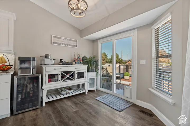 Vaulted ceiling, wood-finish flooring, sliding glass door, bay window, and a built-in beverage cooler
