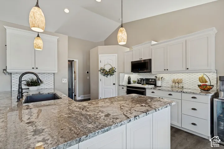 Vaulted ceilings, pendant lighting, white cabinetry, granite countertops, and a white geometric tile backsplash