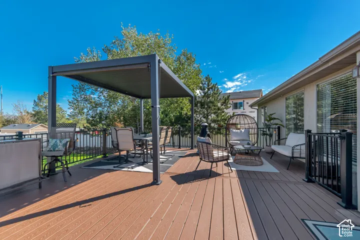 Expansive composite deck featuring a pergola, black metal railing, and exterior lighting
