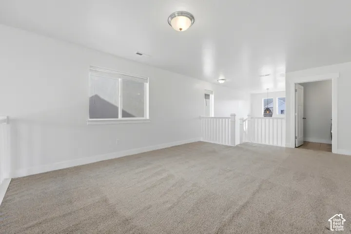 Carpeted loft area with white balusters, overhead lighting, and white trim