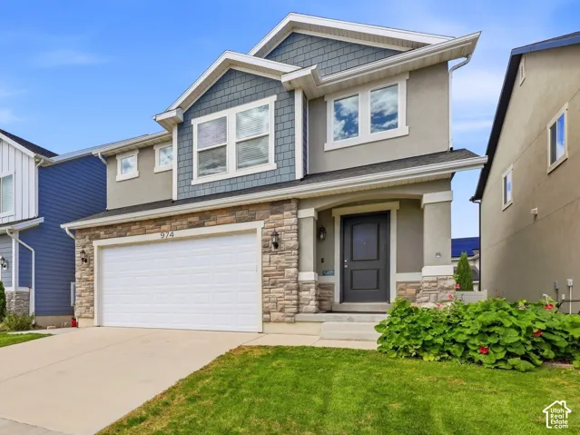Two-story property featuring a stone and stucco facade, a two-car garage, and a covered entry