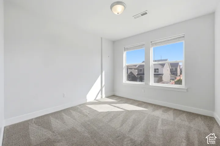 Recessed lighting, light-toned carpeting, and dual windows with blinds