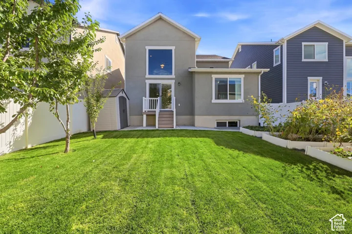 Expansive green lawn, multi-level home exterior, rear deck with steps, large upper-level window, lower-level windows, privacy fencing