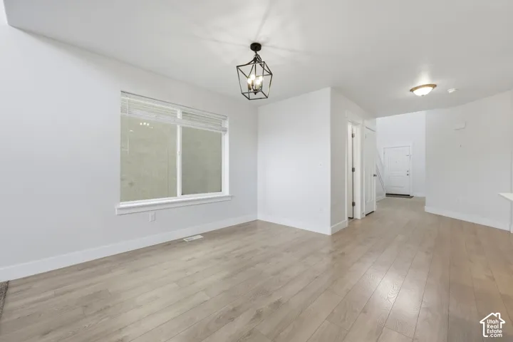 Wood-finish flooring throughout, bright white walls, and a contemporary black geometric light fixture