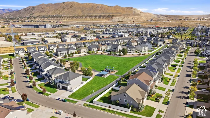 Neighborhood featuring a central green space, residential streets with sidewalks, and a backdrop of mountains