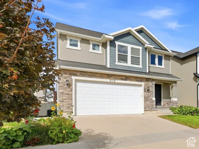 Multi-level residence featuring a two-car garage, stone and siding exterior, and a concrete driveway