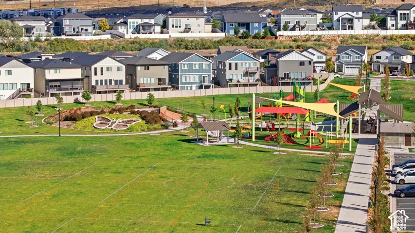 Expansive green space with manicured lawn, dedicated playground area, and sheltered picnic spaces