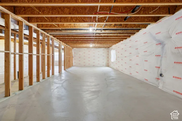 Unfinished basement featuring wood framing, concrete flooring, exposed ceiling joists, and insulated walls