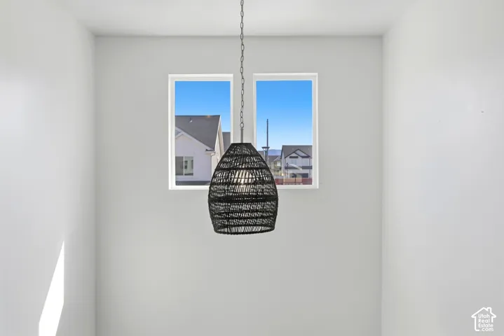 Two upper windows with white trim, a black woven pendant light fixture, and light gray painted walls