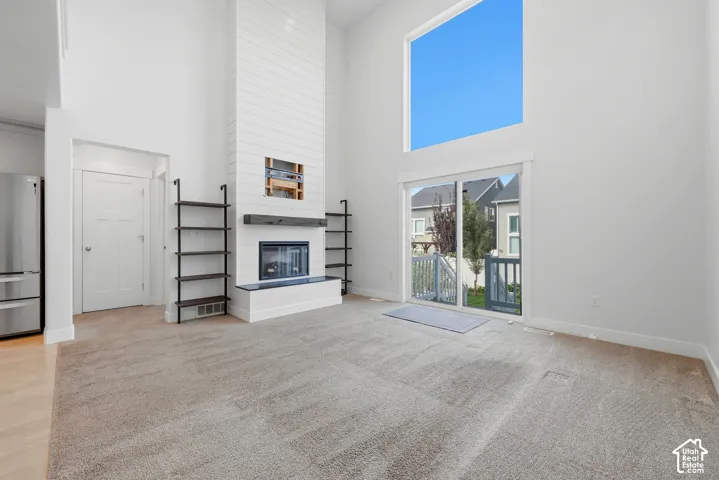 Vaulted ceilings enhance the bright living area, featuring a modern fireplace with a shiplap surround and a wood mantel