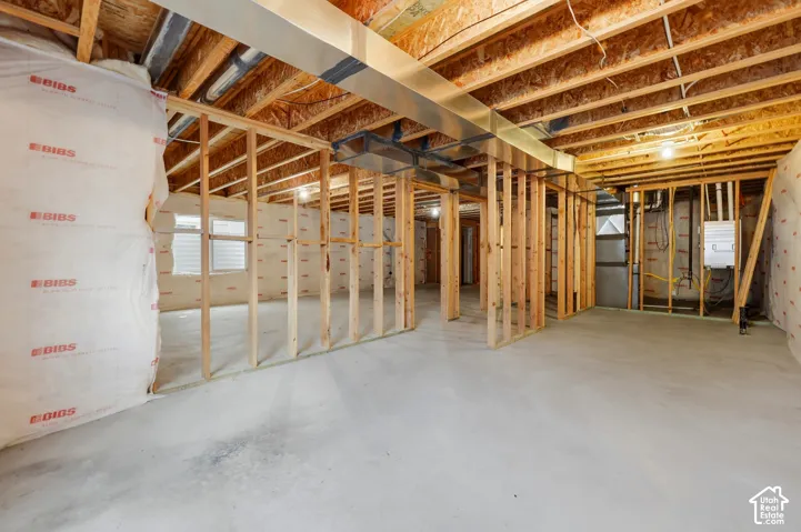 Unfinished basement with concrete flooring, exposed wood framing, ceiling joists, and visible ductwork