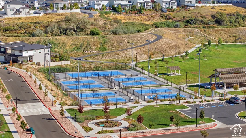 Multiple pickleball courts, expansive green space, paved walking paths, covered picnic structures, and dedicated parking