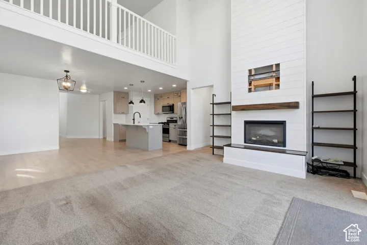 Great room with high ceilings, a fireplace featuring a wood mantel and shiplap surround, and built-in shelving