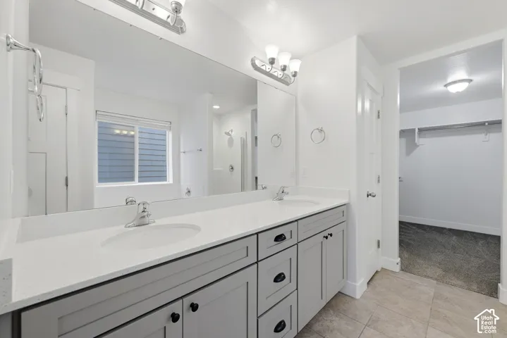 Double vanity with light gray cabinetry, integrated sinks, white countertops, and chrome fixtures