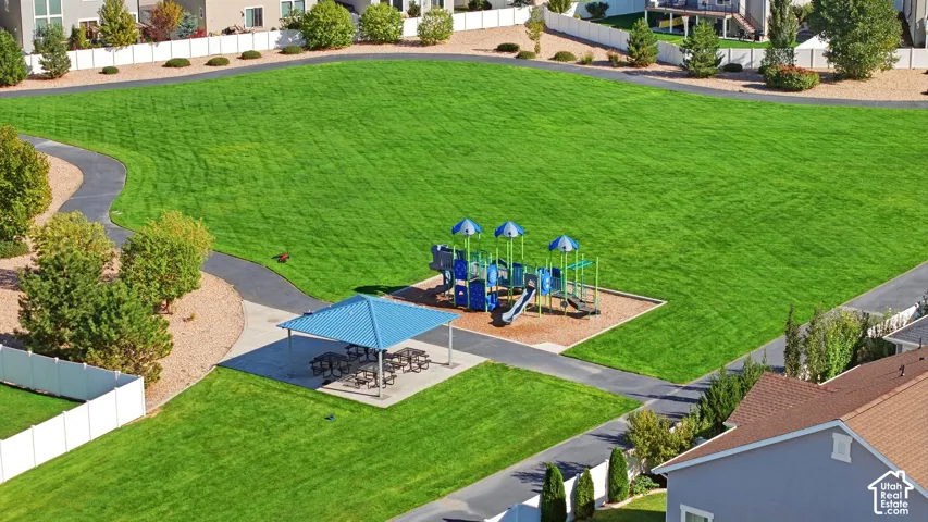 Expansive green space featuring a playground, shaded picnic area, and paved walking paths