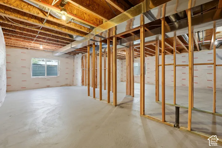Unfinished basement with concrete flooring and wood framing