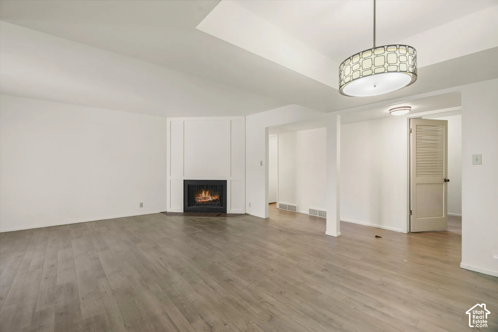 Vaulted ceiling, wood-finish flooring, built-in fireplace, contemporary drum pendant light, and recessed lighting