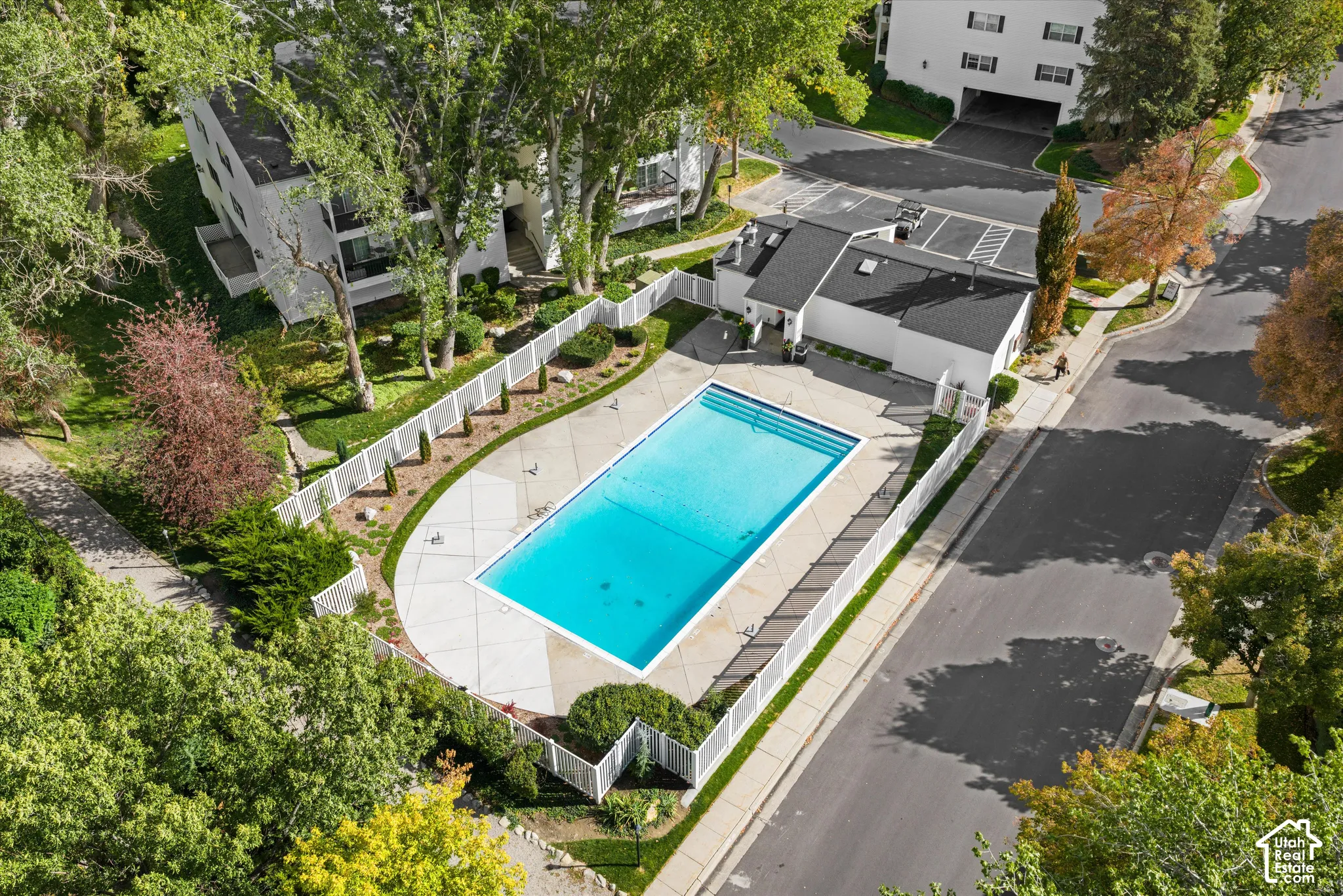 Outdoor swimming pool with a surrounding concrete deck, enclosed by white fencing