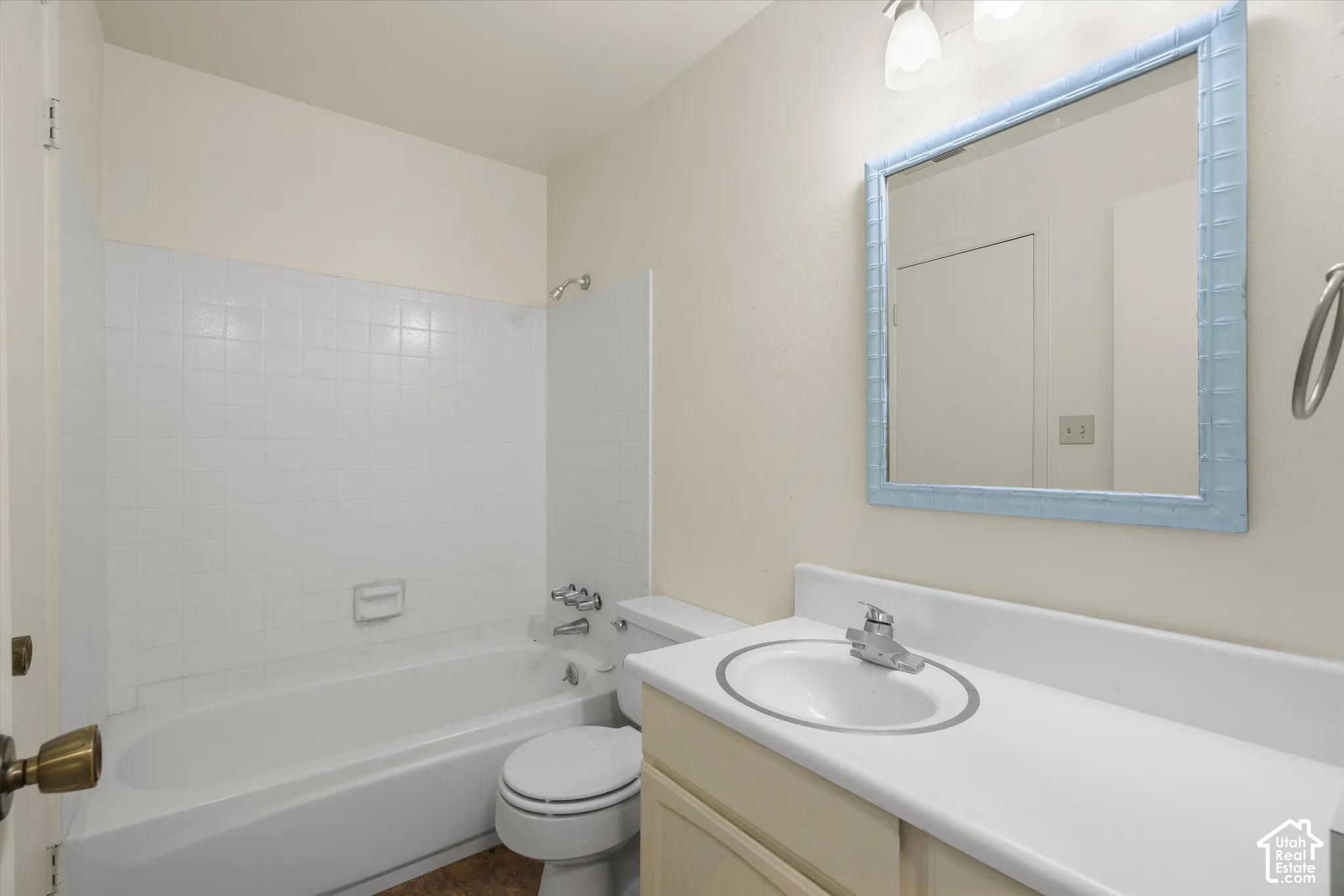 Bathroom featuring a full bathtub with white tile surround, a built-in vanity with integrated sink, and an overhead light fixture