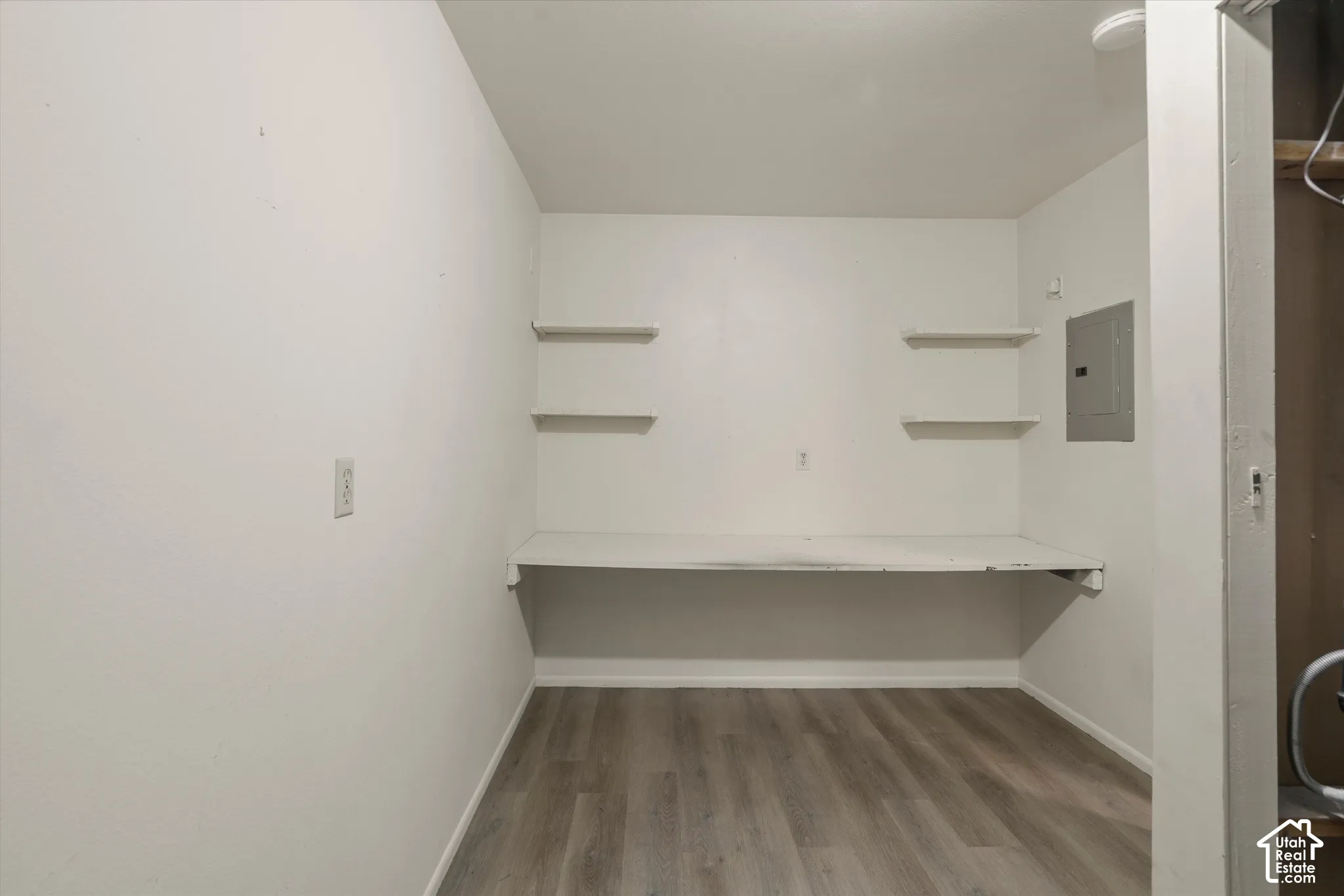 Built-in desk with shelving, wood-finish flooring, and white walls