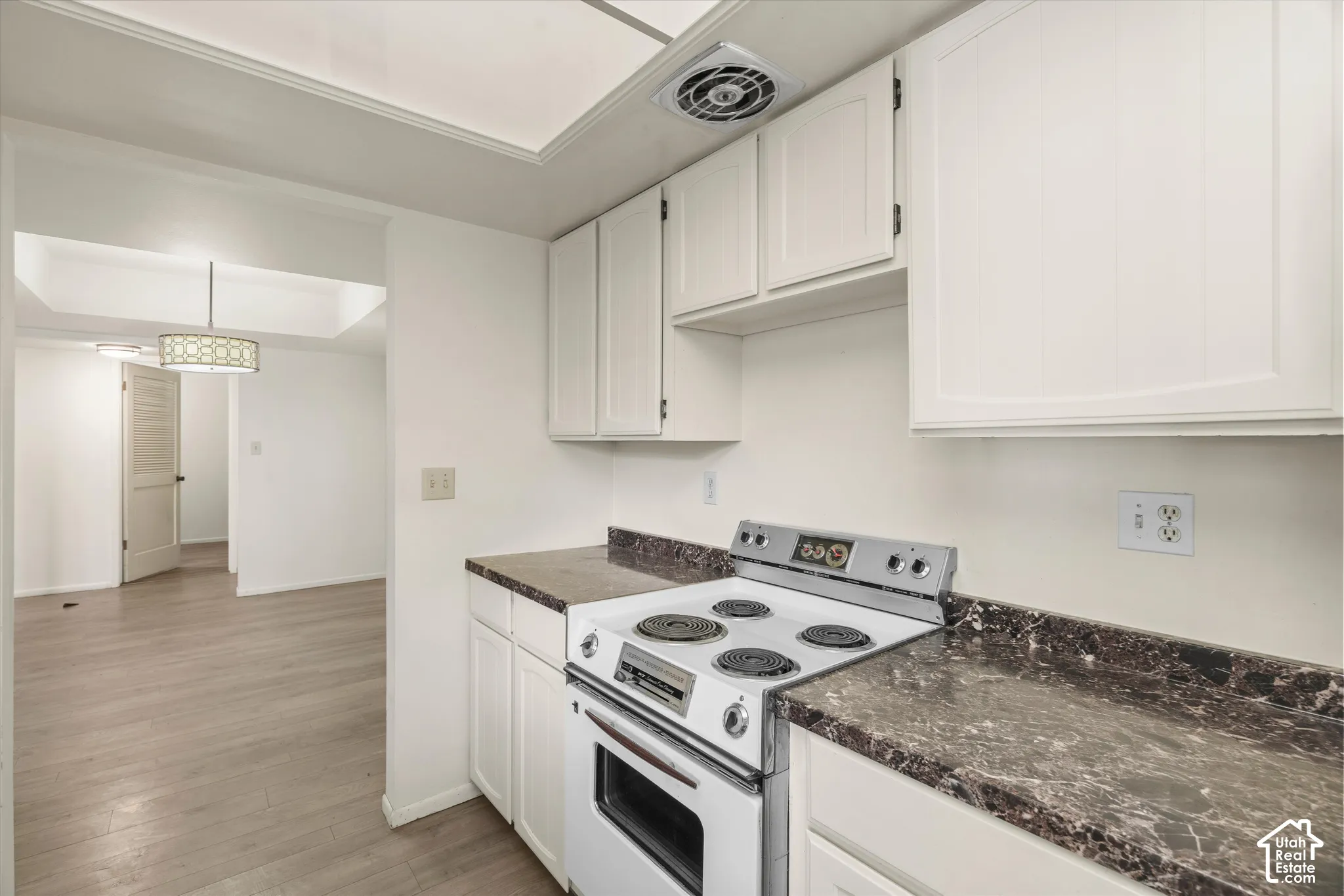 Kitchen featuring white cabinetry, dark speckled countertops, and an electric range