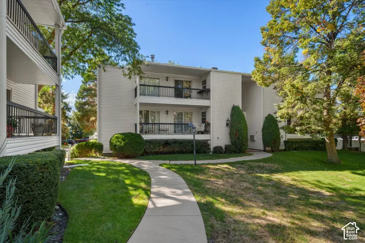Exterior showcasing multiple balconies with black railings, white horizontal siding, and a curved concrete pathway