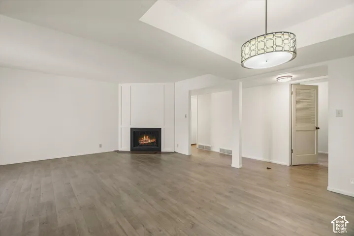 Vaulted ceiling, wood-finish flooring, built-in fireplace, contemporary drum pendant light, and recessed lighting
