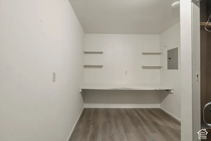 Built-in desk with shelving, wood-finish flooring, and white walls