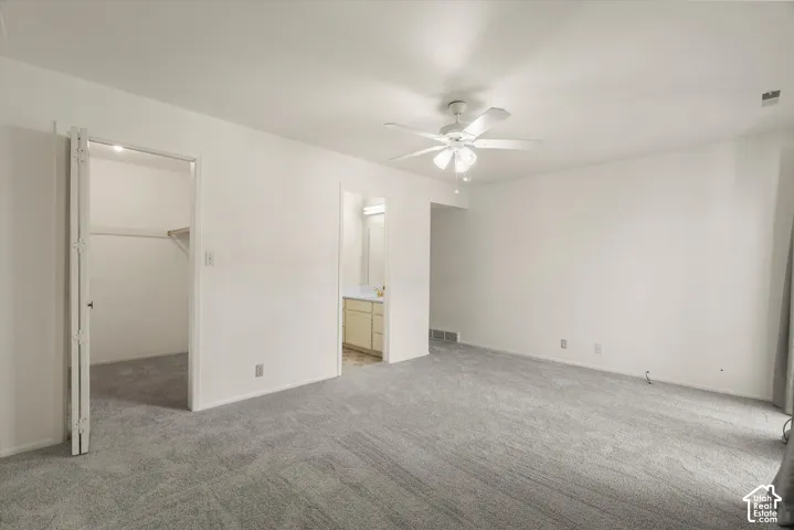 Plush grey carpeting, white wall finishes, and a ceiling fan with integrated lighting