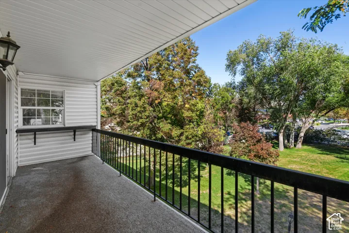 Covered balcony featuring a textured floor, a black metal railing, and a built-in shelf
