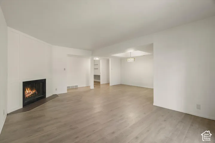 Fireplace with a dark hearth, wood-finish flooring, recessed lighting, and a decorative ceiling fixture