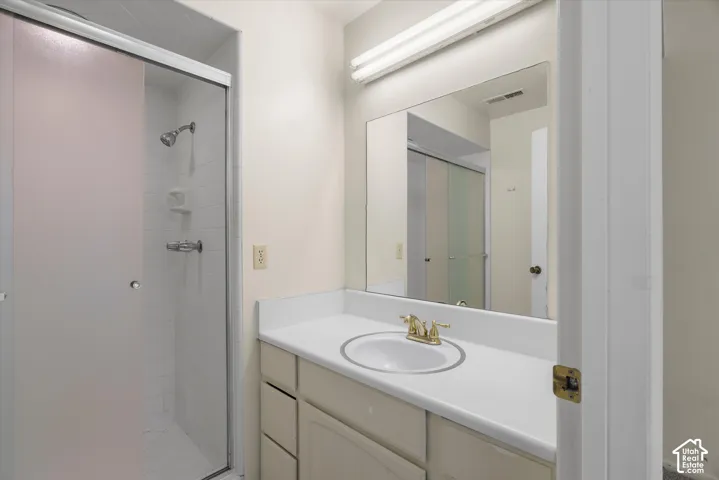 Vanity with an integrated sink and brass-finish faucet, framed mirror, and a shower with a clear glass enclosure