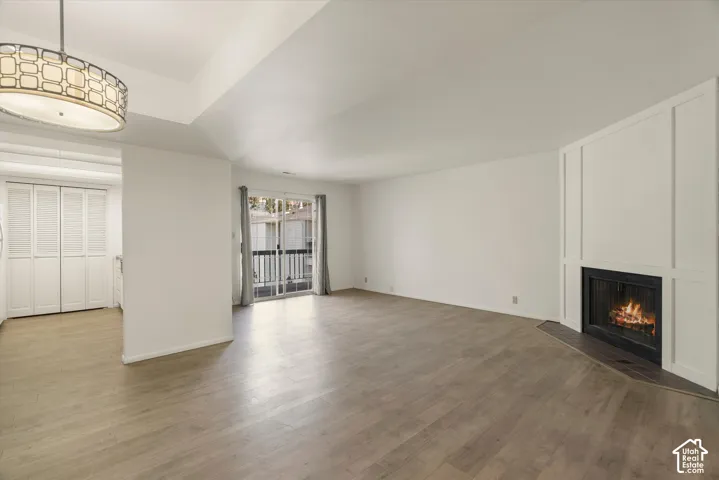 Spacious living area featuring wood-finish flooring, a fireplace with a paneled surround, and a sliding glass door to an outdoor balcony