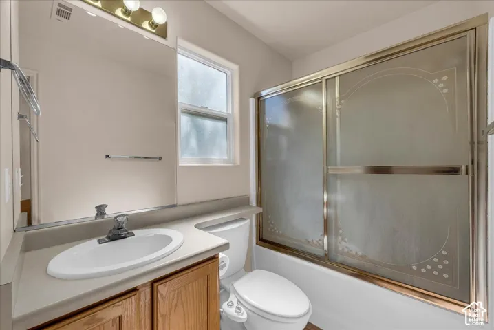 Bathroom with a vanity featuring a single basin sink, a large wall-mounted mirror, and a window with frosted glass