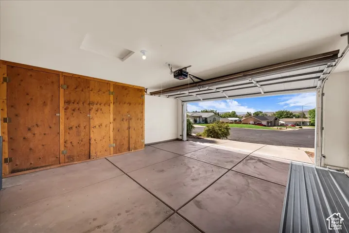 Attached garage with concrete flooring, built-in wooden storage cabinets, and automatic garage door opener