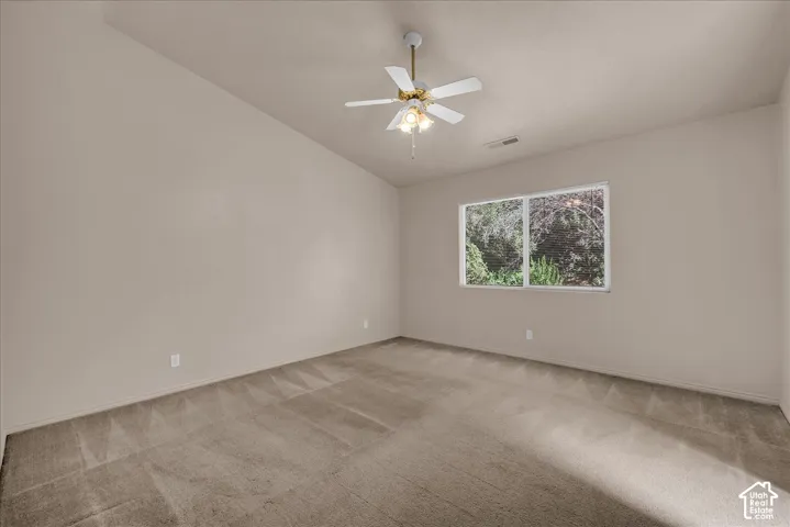 Vaulted ceiling with a ceiling fan, neutral wall paint, and carpet flooring