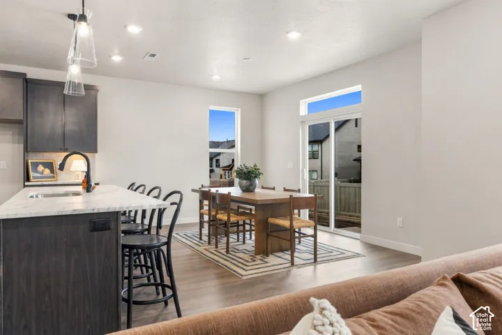 Kitchen island with light-toned countertop, dark wood-finish cabinetry, and contemporary pendant lighting
