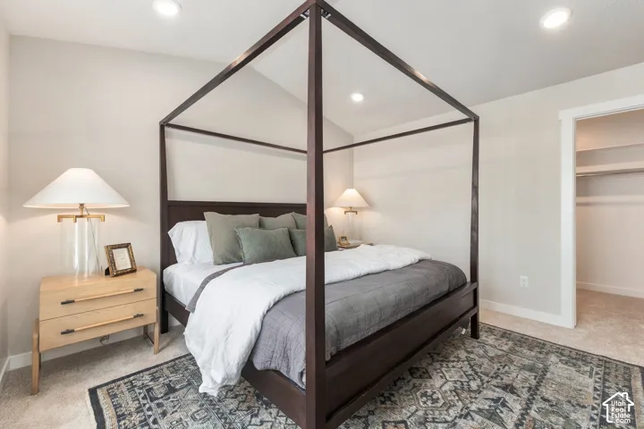 Recessed ceiling lighting, light-toned wall paint, carpeted flooring, and a walk-in closet with built-in shelving